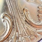 真鍮の地肌に白い塗料がかすかに残るシャンデリア本体のアップ。細部まで施された精巧なエンボス装飾の質感。